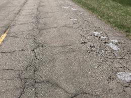 Cracked gray road with grass on both sides