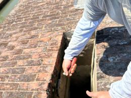 An employee uses a tool on a brick structure