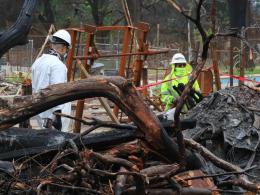Two people cleaning up debris from wildfire.