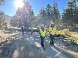 Secretary Haaland in safety gear waking with others along a dirt mountain road. 