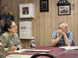 Secretary Haaland sits at a table jotting down notes and faces a speaker offscreen during a meeting. 