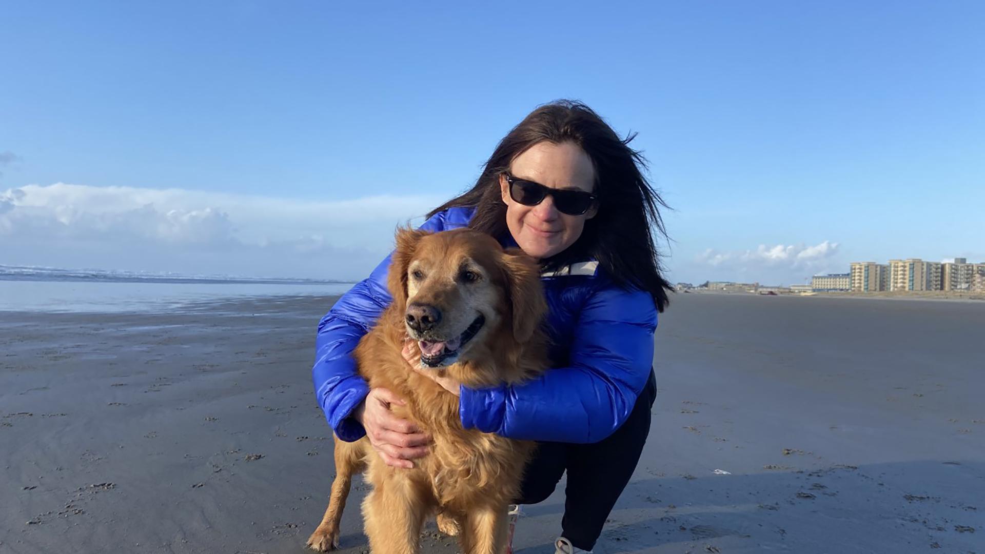 Erin hugs her dog on a beach