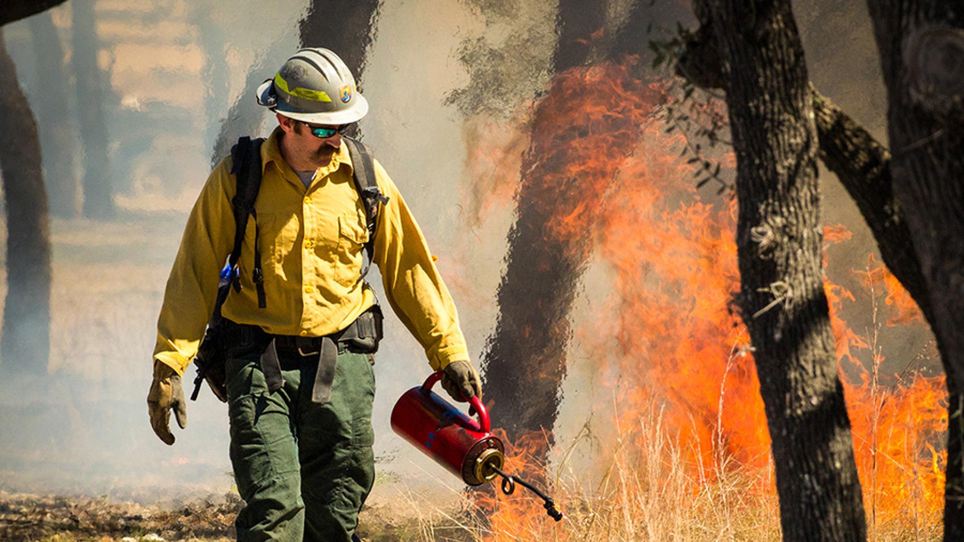 A wildland firefighter with the U.S. Fish and Wildlife Service helps private landowners adjacent to the Balcones Canyonlands National Wildlife Refuge set a prescribed fire to manage vegetation and reduce the risk of an extreme wildfire. He holds a drip to