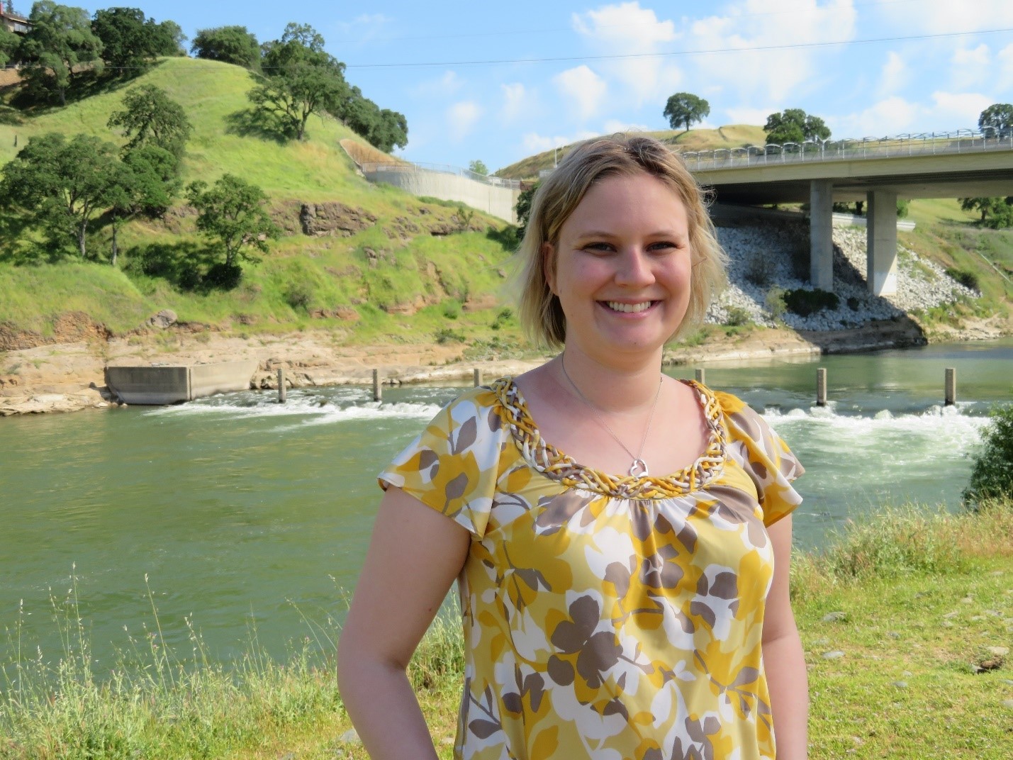 Amanda Becker stands in front a stream and bridge.
