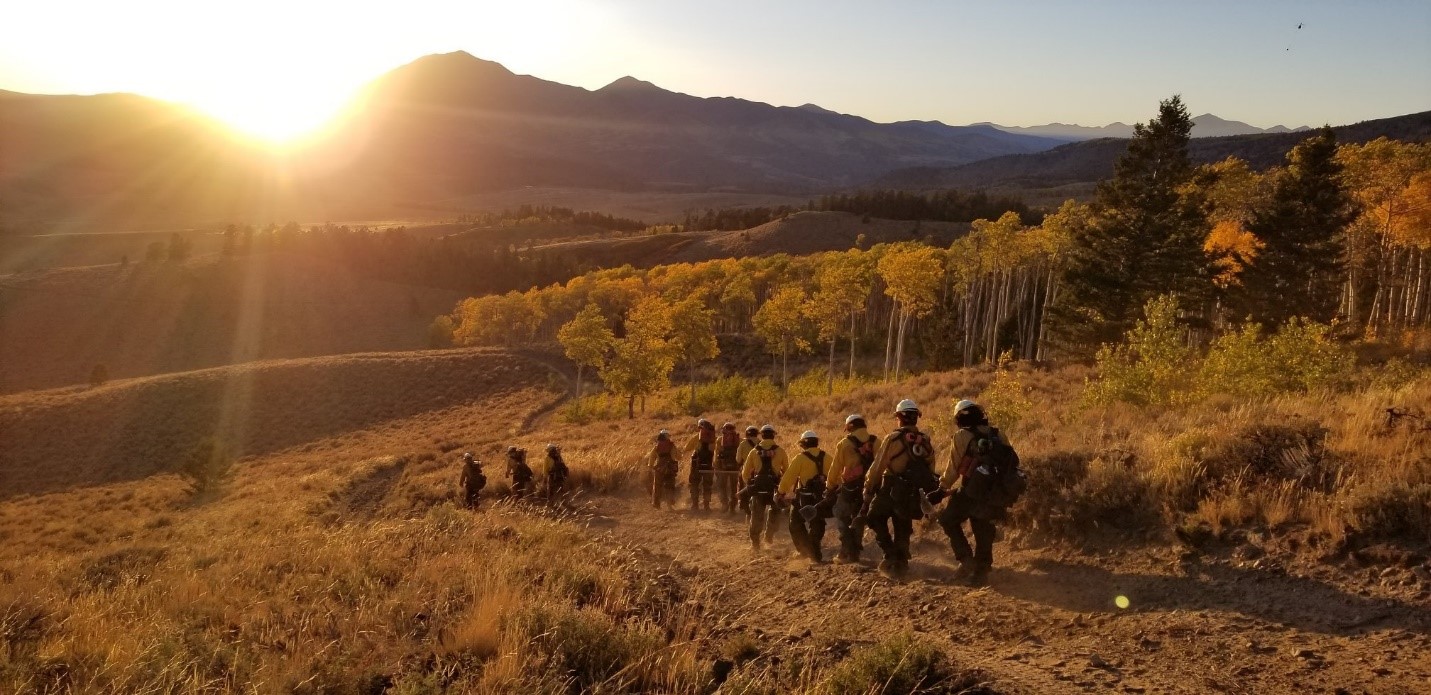 Photo by Bureau of Indian Affairs. Hand crew walks toward the mountains at sunset.