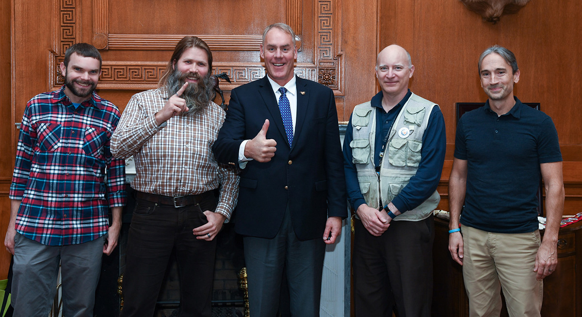 Four men stand with Secretary Ryan Zinke in his office.