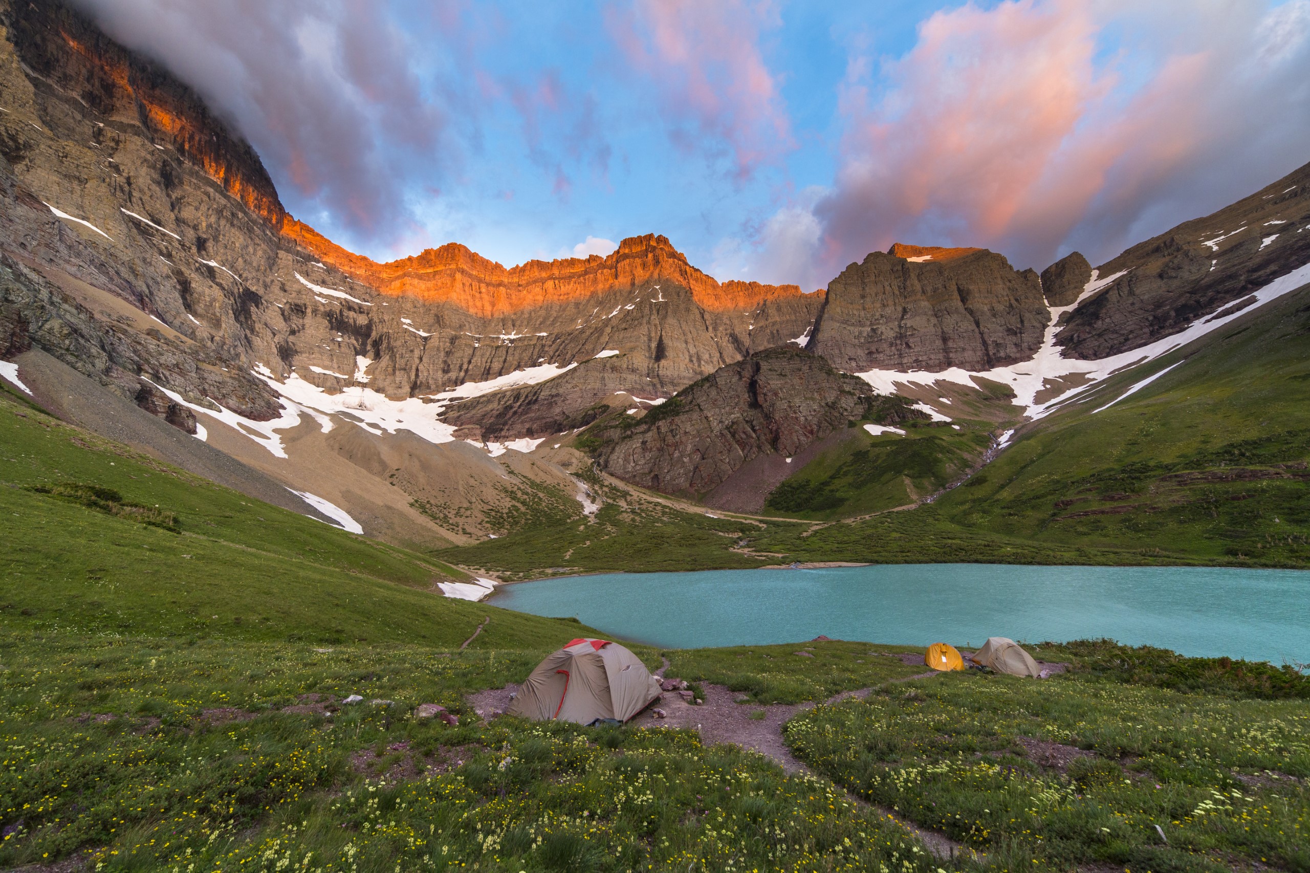 tents camped near a blue lake surrounded by mountains