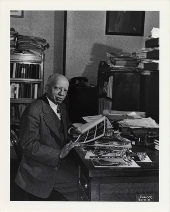 Dr. Woodson sits at his desk in his study.