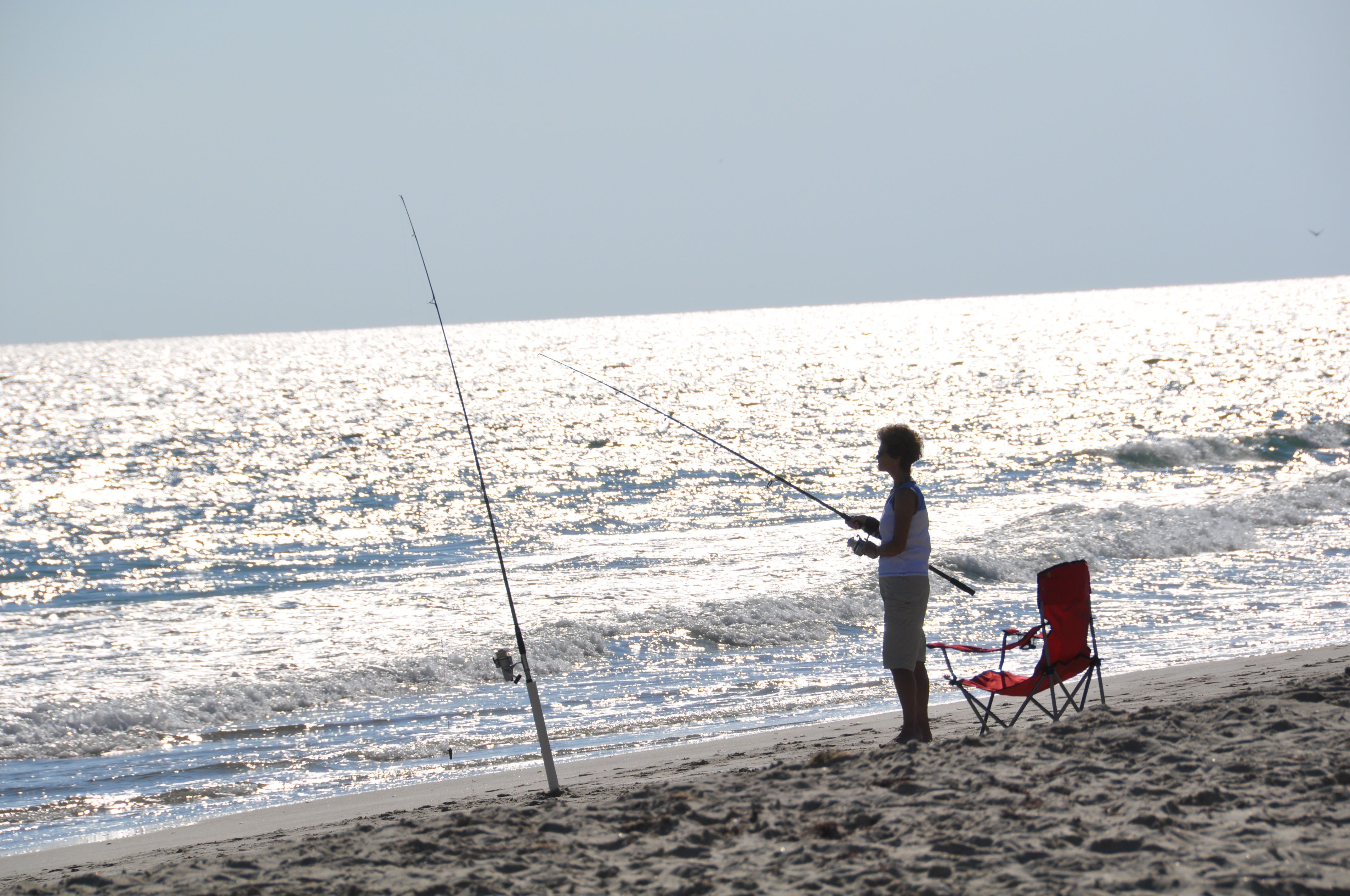 Person fishing on the ocean shoreline.