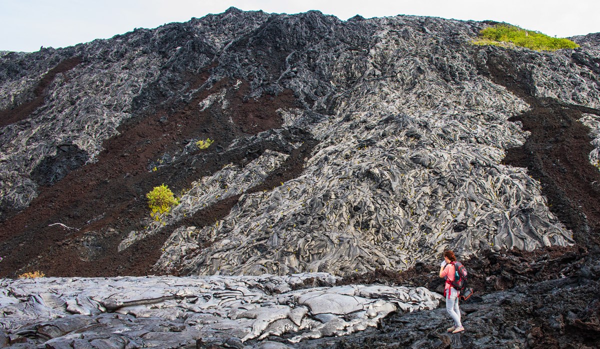 A person stands next to solidified lava flows.