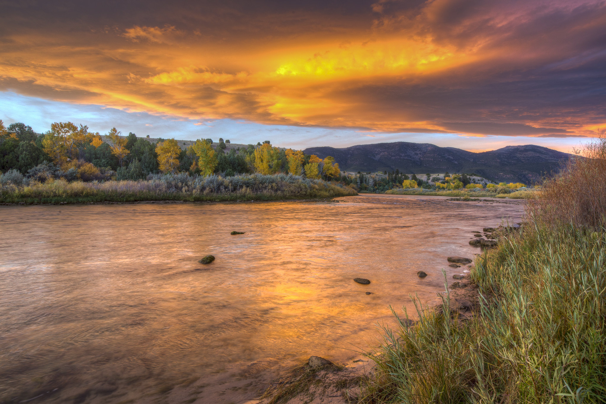 Orange and dark purple sky reflects on the Green River. 