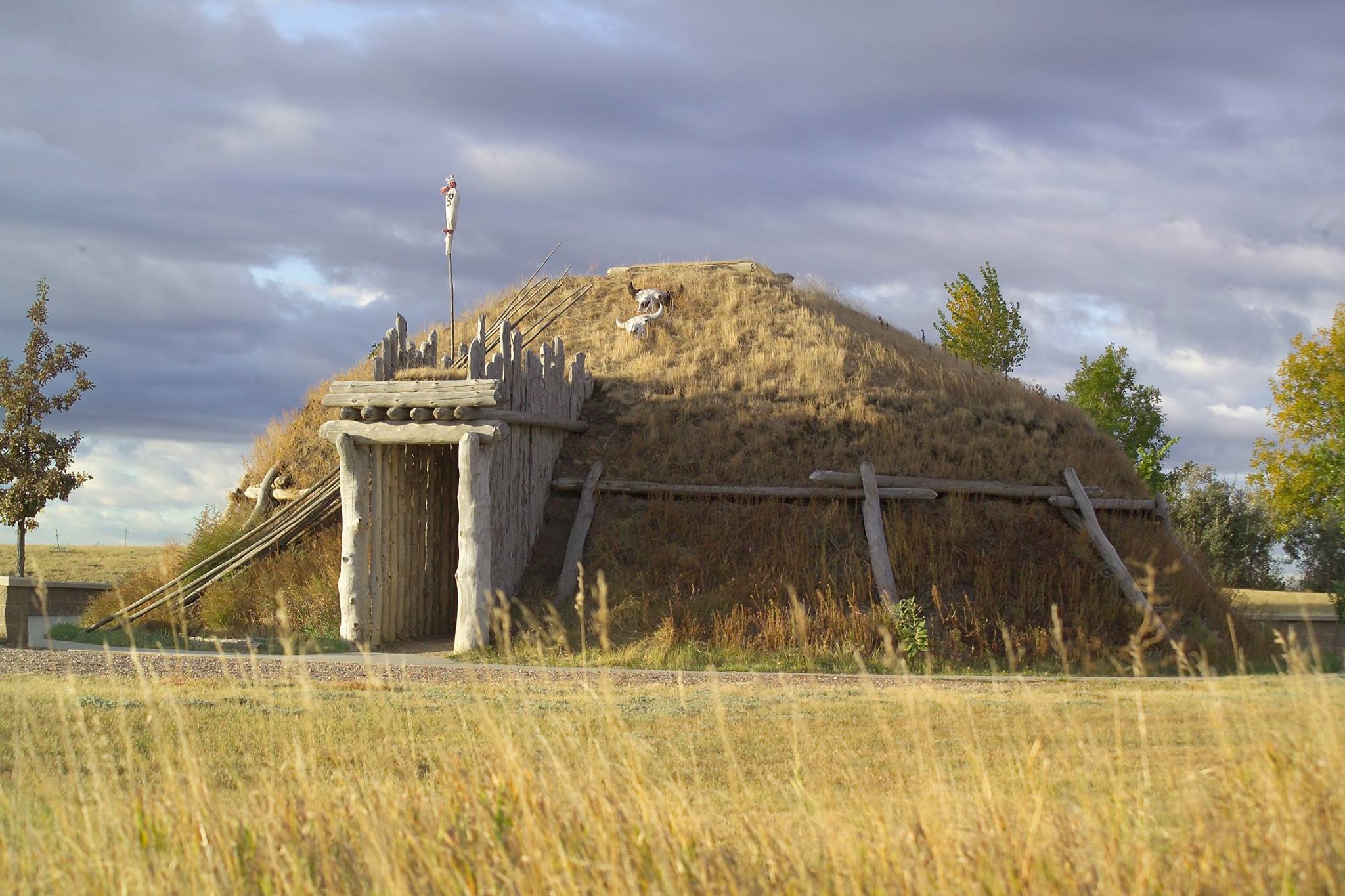 A round lodge covered in grass and dirt with a wooden entry ways.