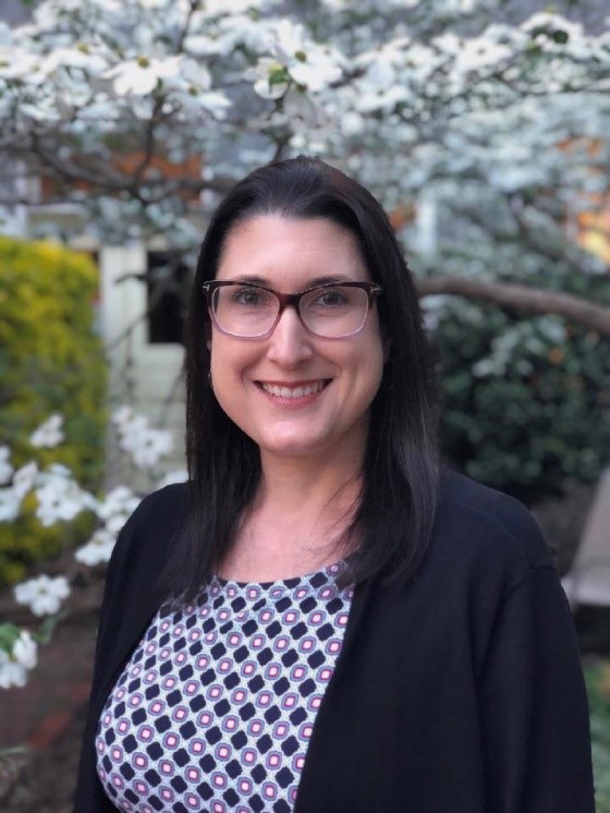 Portrait of Melissa Schwartz in front of cherry blossoms. 