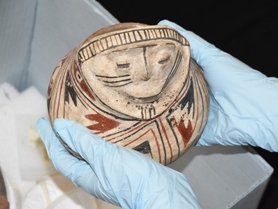 Painted prehistoric pot of a person.