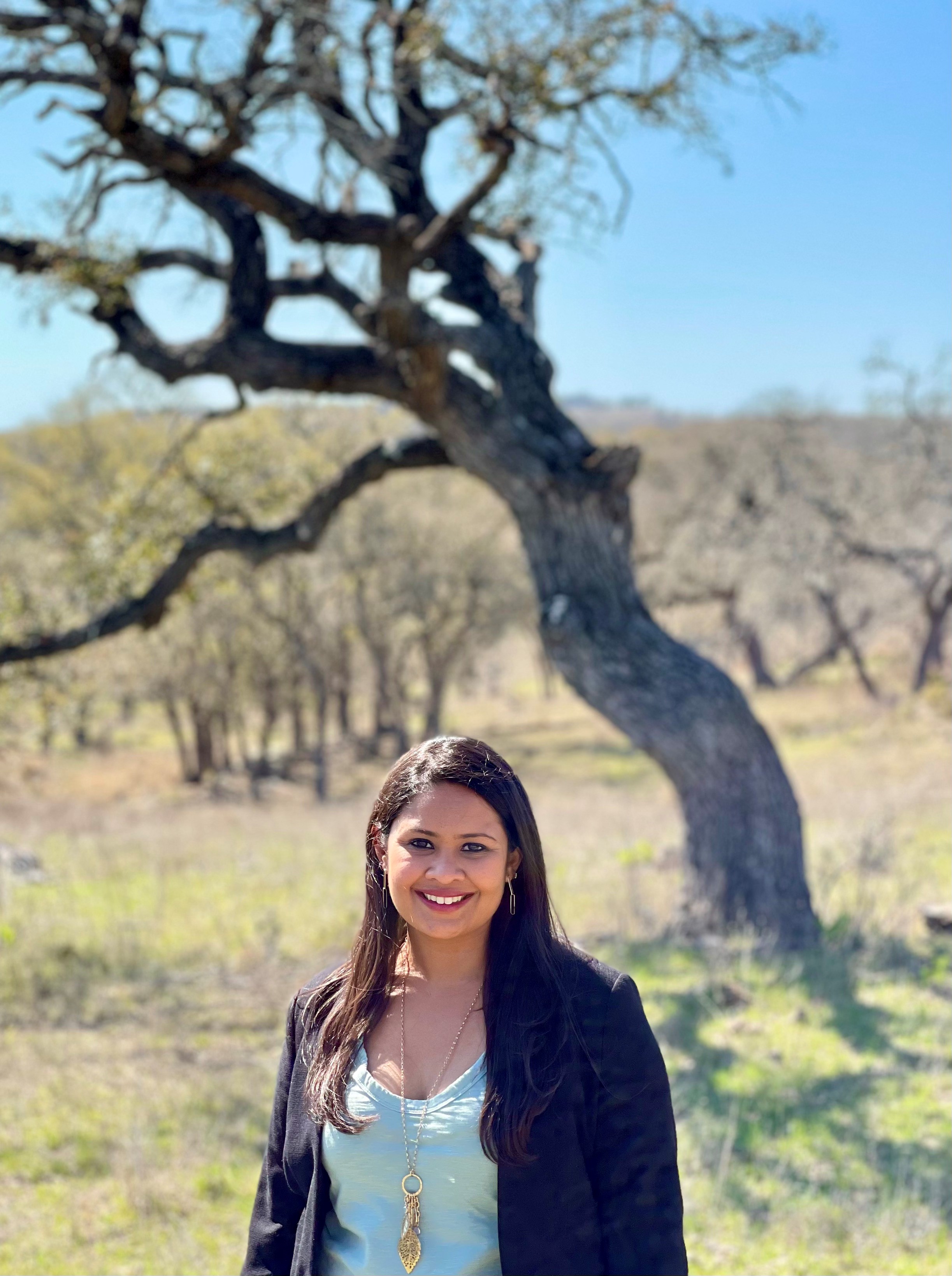 Mili Gosar stands in front of trees under a blue sky.
