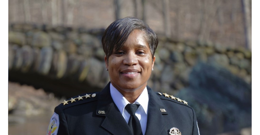 Pamela A. Smith, Chief of the U.S. Park Police, stand in front of a stone bridge in Rock Creek Park.