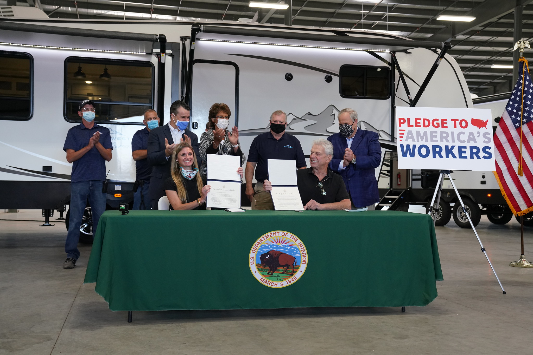 A small group of people stand around a table in an RV factory.