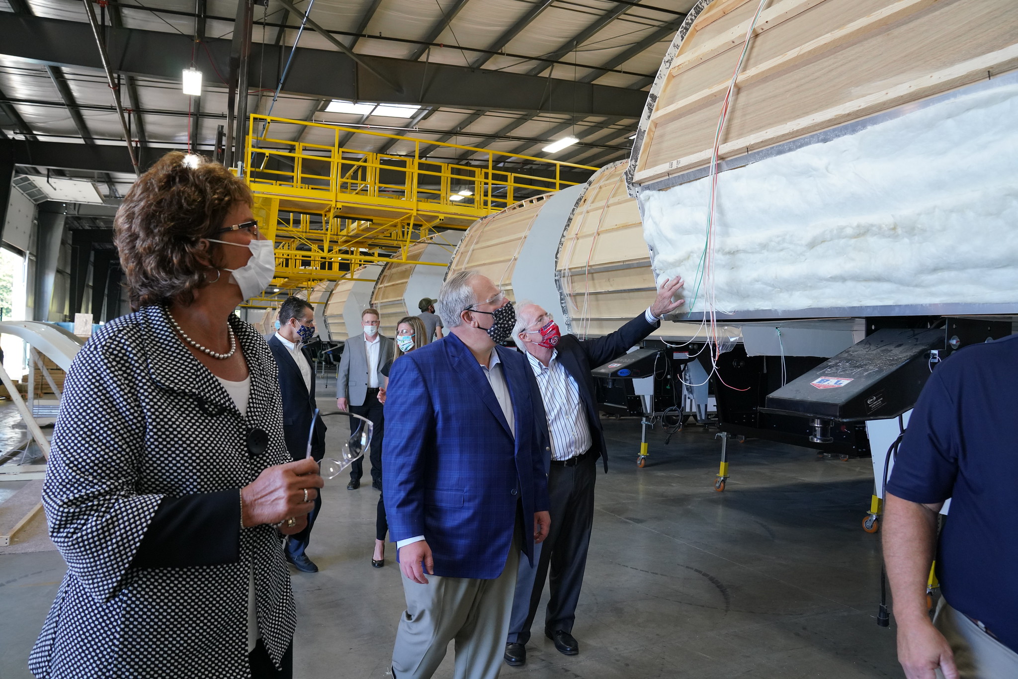 A small group of people walking inside a large factory.