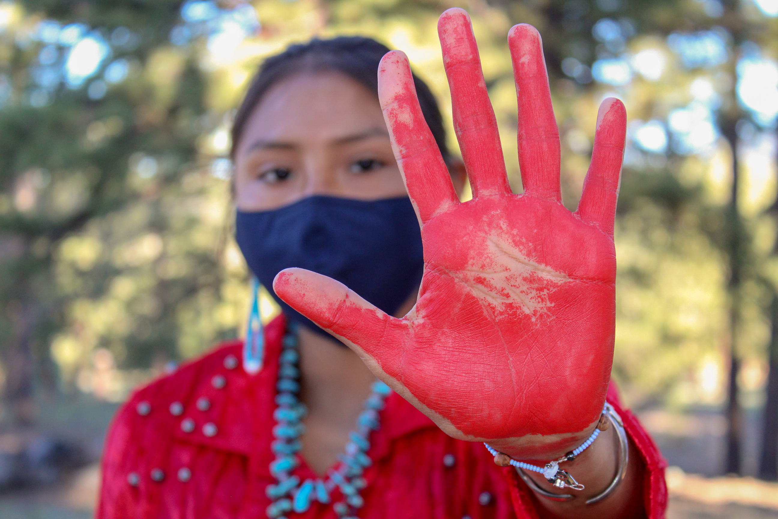 Young woman holds her red-painted palm to the camera