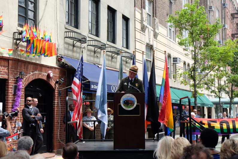 Director Jarvis speaks to a crowd at the ceremony while standing behind a wooden podium