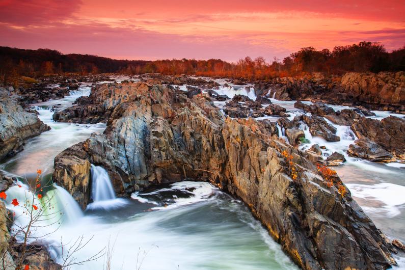 The Potomac River rushes over rocks under a pink, autumn sky