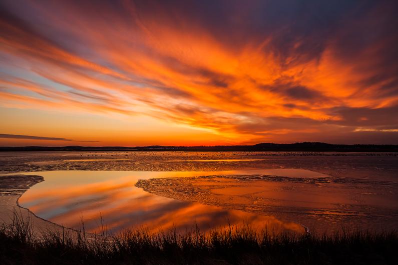 A bright orange sunset over a winding river