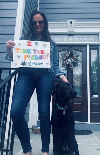 Jennifer Ackerman from Human Capital, outside home entrance holding the I Took the Pledge sign, big, black dog sitting by her side. 