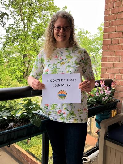  Agnes Wanderer from SOL standing on a deck holding the I took the Pledge #DenimDay sign. 