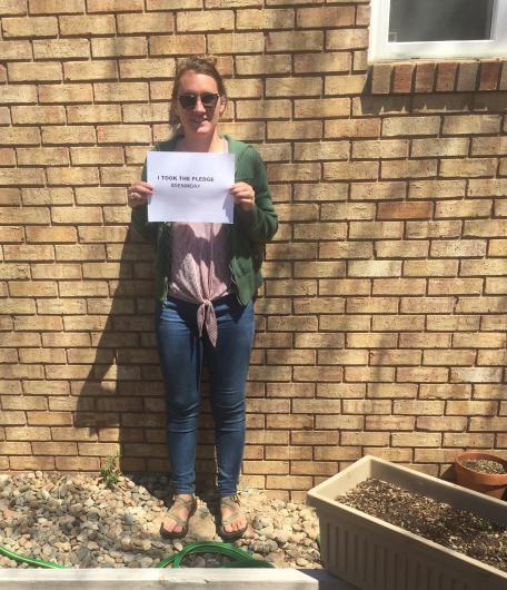 Amber Furness from FWS standing by wall holding the I Took the Pledge #DenimDay sign. 