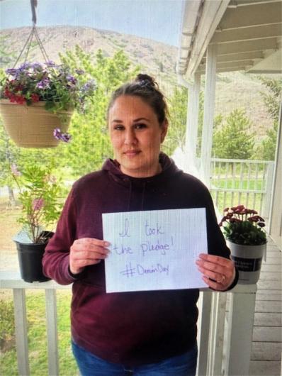 Cody Leonard from USBR, standing on a porch holding the I took the Pledge #DenimDay sign. 