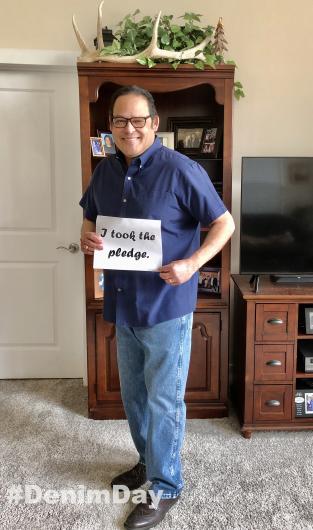 David Vela from NPS holding the I took the Pledge #DenimDay sign. 