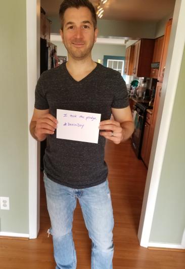 Thomas Ziehnert from OCR holding the I Took the Pledge #DenimDay sign. 