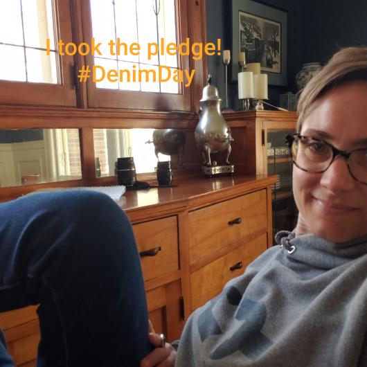 Lark Weller from NPS sitting showing her jeans with the I took the Pledge #DenimDay sign written on the image.  