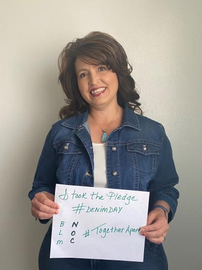 Dani Ramirez-Montoya standing with the I Took The Pledge #DenimDay #TogetherApart NOC sign. sign