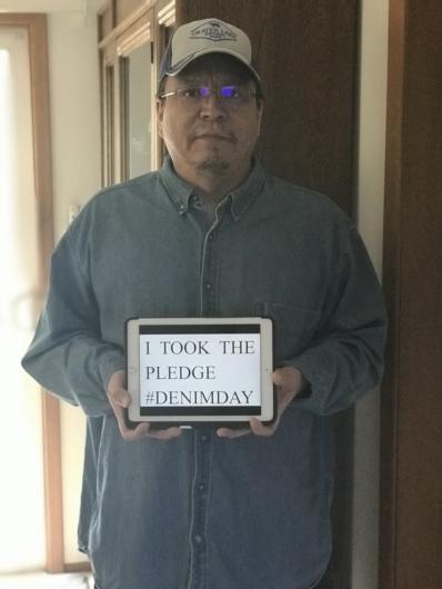 Dale Sebastian from BIA holding the I took the Pledge #DenimDay sign. 