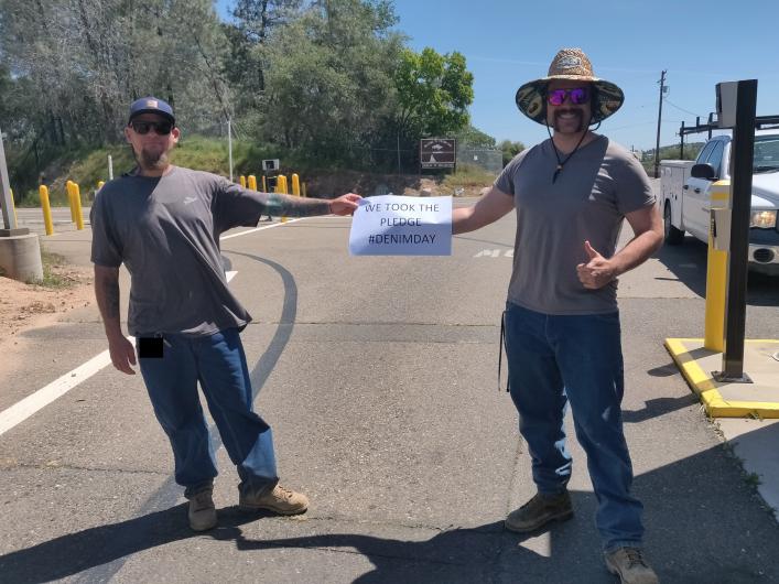Two men from USBR, outside on the street holding the I took the Pledge #DenimDay sign. 