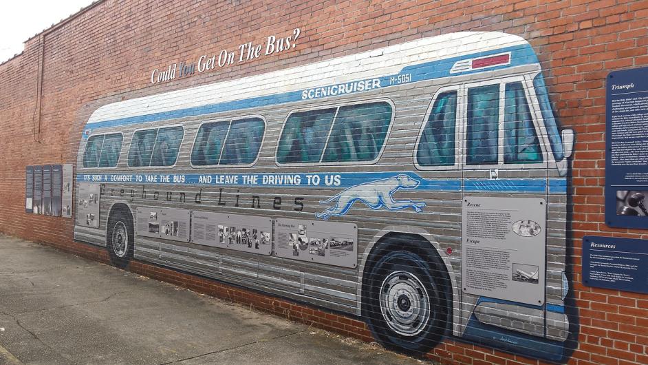 Photo of historic mural of a large Greyhound bus painted on a long brick wall.