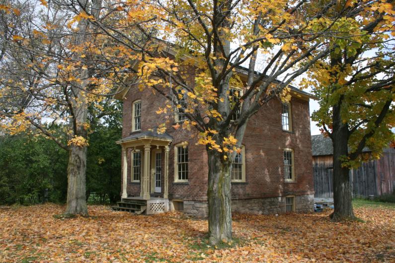 Harriet Tubman National Historical Park Photo of a small brick house with a porch surrounded by trees showing their autumn colors.