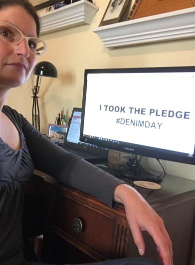 Heidi Nelson from FWS sitting next to computer, written on screen I Took the Pledge #DenimDay.