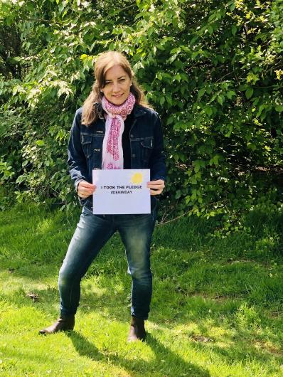 Isabel Long from OCR, outside holding the I Took the Pledge #DenimDay sign. 