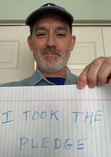 Jerold Gidner from OST holding the I took the Pledge #DenimDay sign. At his back, wildlife set up exhibit item