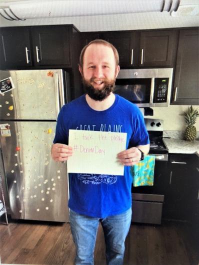 Jed Gibson from OCR in the kitchen holding the I took the Pledge #DenimDay sign. 