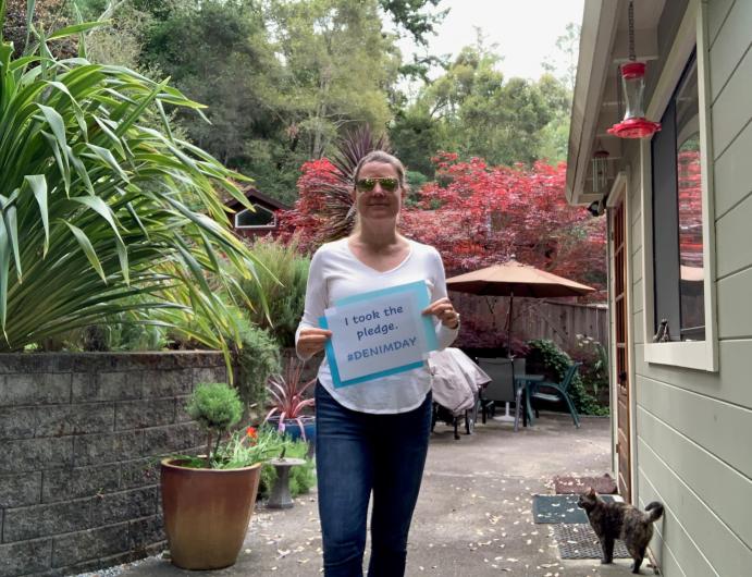 Laura Torresan from USGS, outside in patio, holding the I took the Pledge #DenimDay sign. 