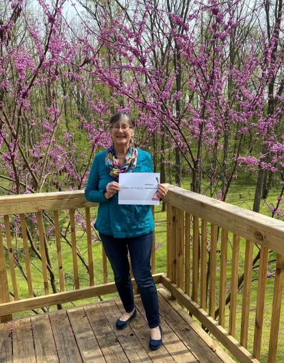 Marcia McNiff from USGS, standing on a deck holding the I took the Pledge #DenimDay sign.
