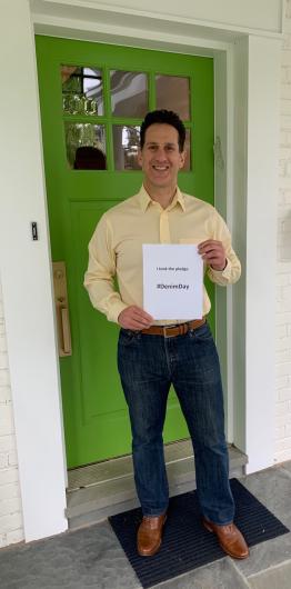 Mark Greenblatt from FWS standing outside green door holding the I took the Pledge #DenimDay sign. 