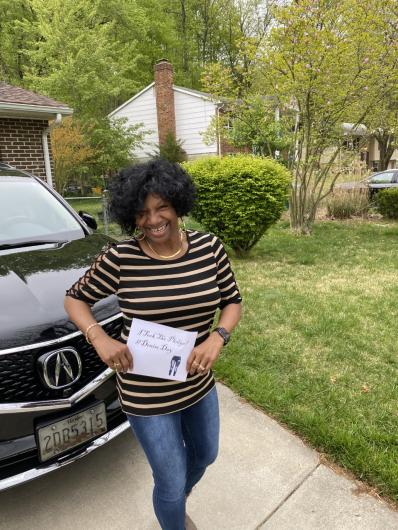 Melba Vaughn from OCR, outside holding the I took the Pledge #DenimDay sign. Jeans are drawn in sign. 