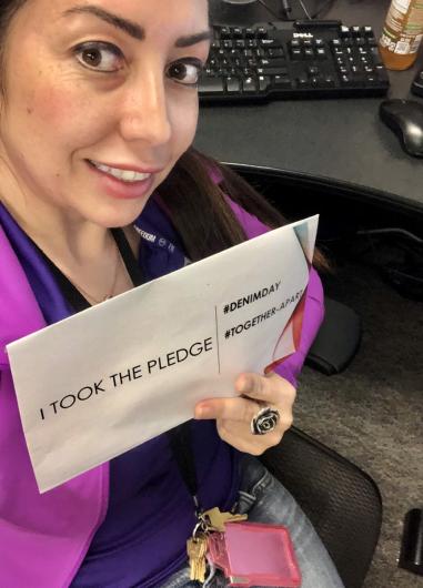 Melissa McKinley from USBR, sitting by computer the I Took the Pledge #DenimDay sign. 