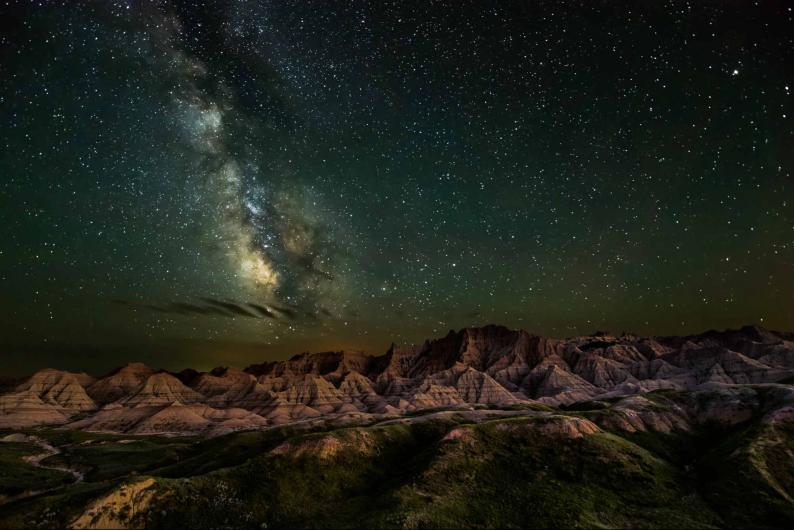 The shining stars of the Milky Way glow over the rocky formations of Badlands National Park.