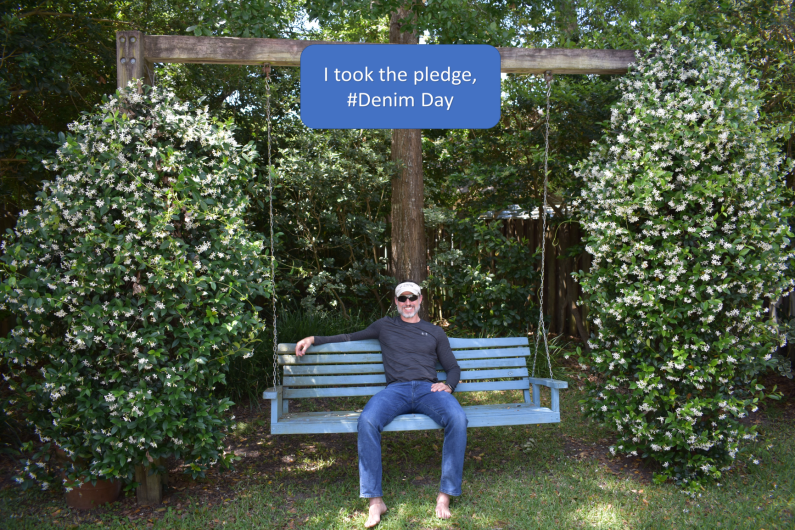 Robert Lachance from OLES sitting outside on a bench. At the top, the I Took the pledge #DenimDay sign. 