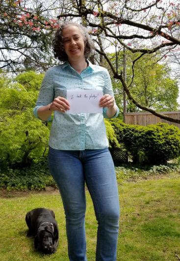 Penni Winberg from OCR, outside holding the I took the Pledge #DenimDay sign. Dog behind her, sitting on the grass. 